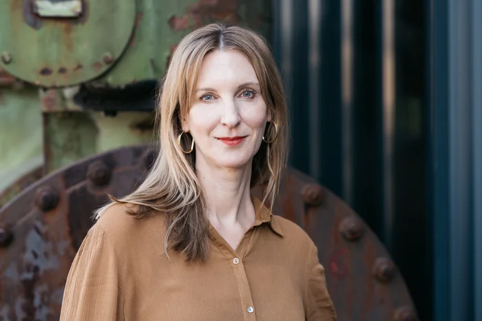 Stephanie Noack stands in front of a rusty machine and looks into the camera.