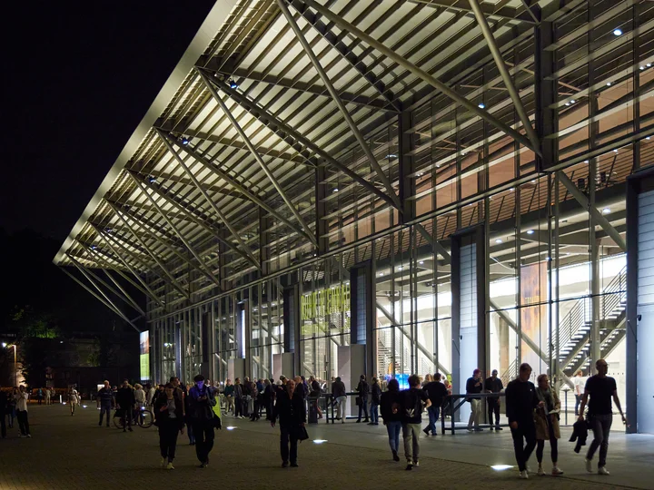 Die Jahrhunderthalle Bochum bei Nacht mit Menschen auf dem Vorplatz