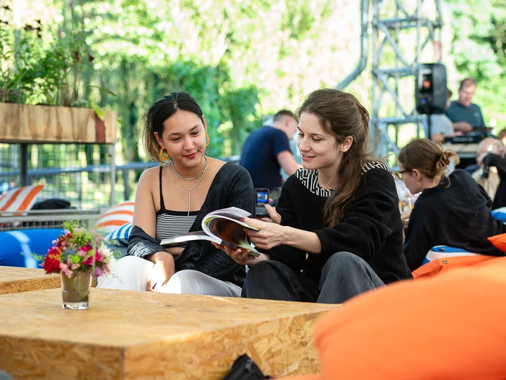 Zwei Besucher:innen auf Sitzsäcken, die in der Ruhrtriennale-Programmbroschüre lesen.